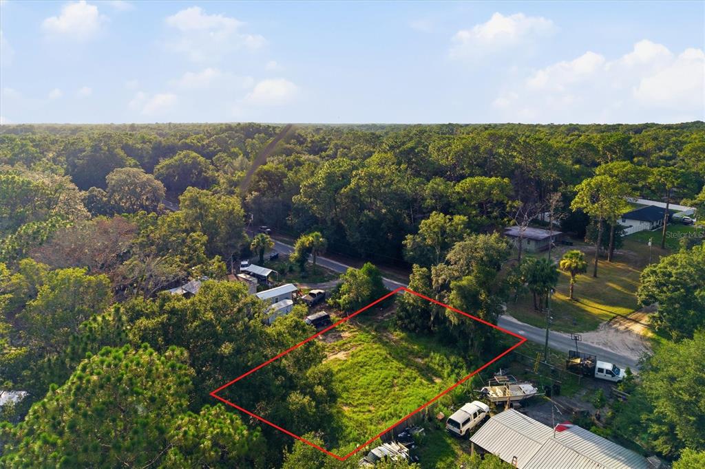 An aerial view shows a rectangular, grass-covered vacant lot outlined in red near a road — 88 W SIMON AVENUE, APOPKA, FL