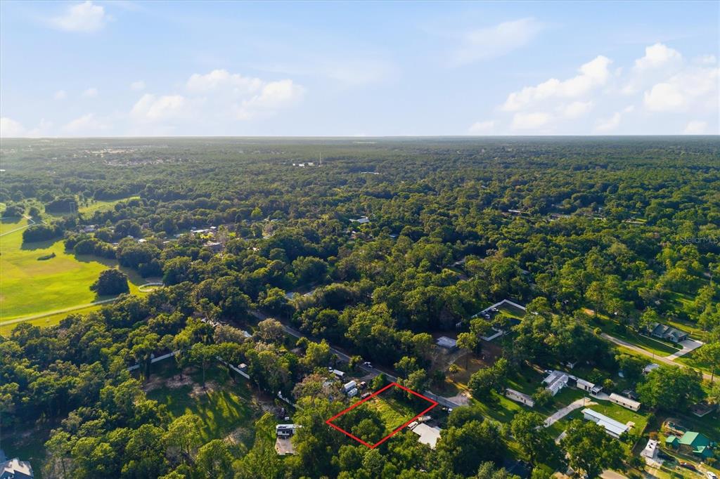 An aerial view shows a rectangular plot of land outlined in red amidst a wooded area — 88 W SIMON AVENUE, APOPKA, FL
