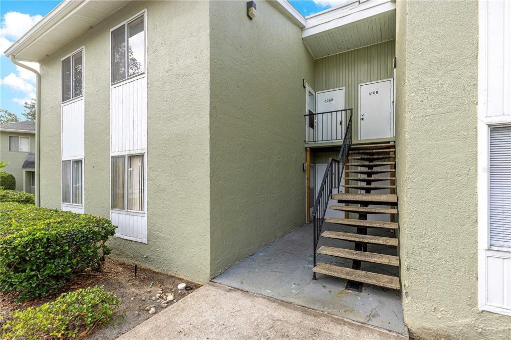 An exterior view of a two-story apartment building with an outdoor staircase leading to upper units — 608 FAIRWAYS CIRCLE UNIT B, OCALA, FL