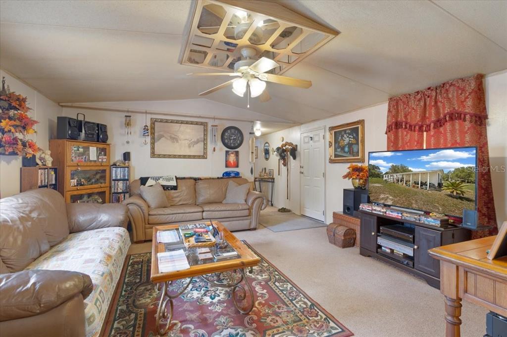 A living room features a beige sofa, a coffee table, and a television on a stand — 187 SE LOXLEY GLEN, LAKE CITY, FL