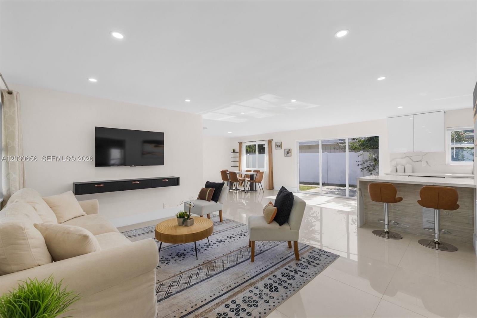 This open-concept living area features a kitchen with a breakfast bar and tile flooring — 416 NE 29th St, Wilton Manors FL 33334, WILTON MANORS, FL