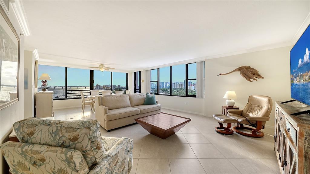 A bright living room features tile flooring, a beige sofa, and floor-to-ceiling windows with water views — 770 S PALM AVENUE UNIT 904, SARASOTA, FL