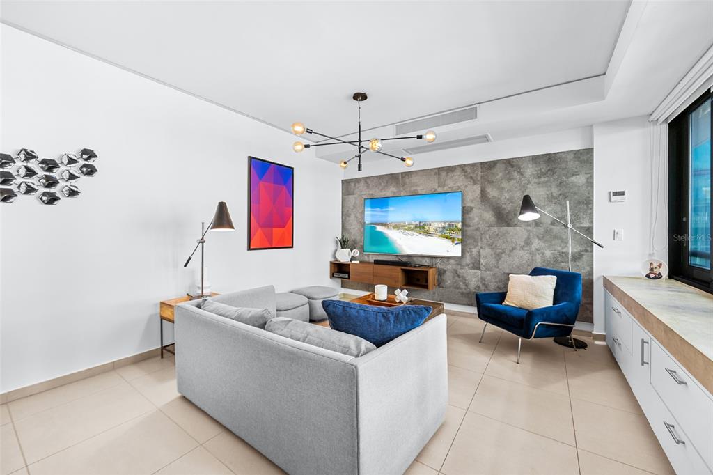 A modern living room features a gray sofa, blue armchair, and a wall-mounted television — 1511 AVENIDA JUAN PONCE DE LEÓN CIUDADELA TORRE 800 UNIT 861, SAN JUAN, PR