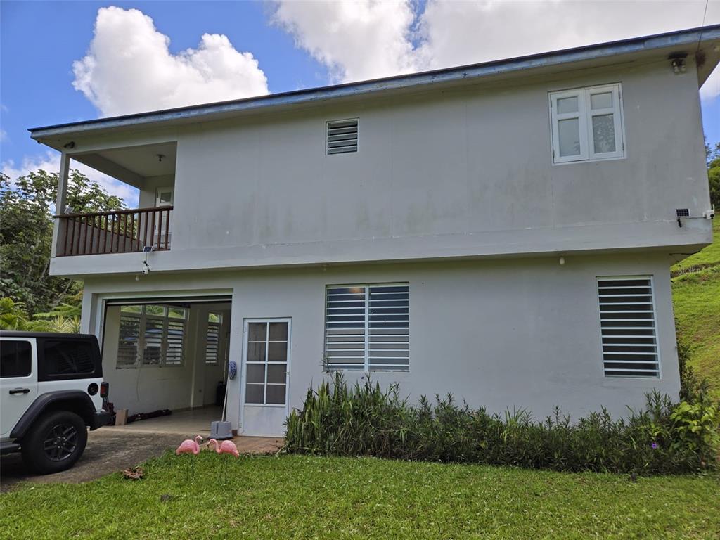 A two-story house with a white exterior, a balcony, a garage, and a grassy yard — Carr 813 KM 2.5 INT, NARANJITO, PR