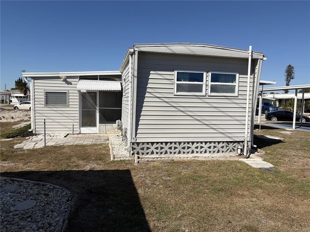 The exterior of a light gray mobile home features a screened porch and lattice skirting — 1862 PALM SPRINGS STREET, SARASOTA, FL