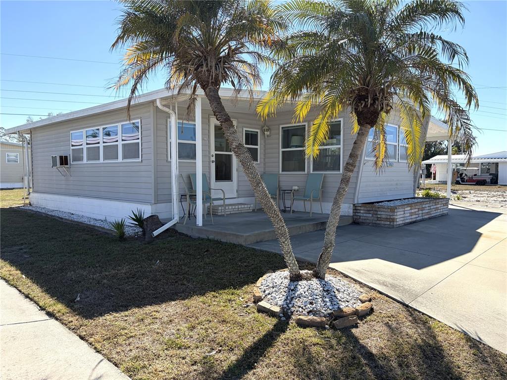 A light-colored mobile home features a concrete patio, two palm trees, and a driveway — 1862 PALM SPRINGS STREET, SARASOTA, FL