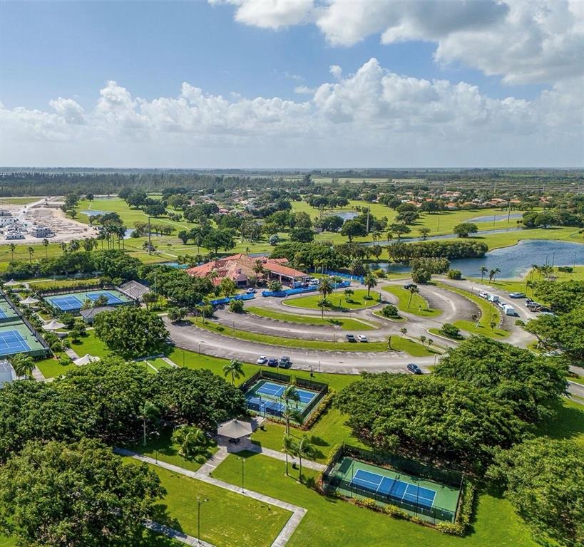 Aerial view of a clubhouse complex with tennis courts, parking, and surrounding golf course grounds — 1970 SE 23RD TERRACE, HOMESTEAD, FL
