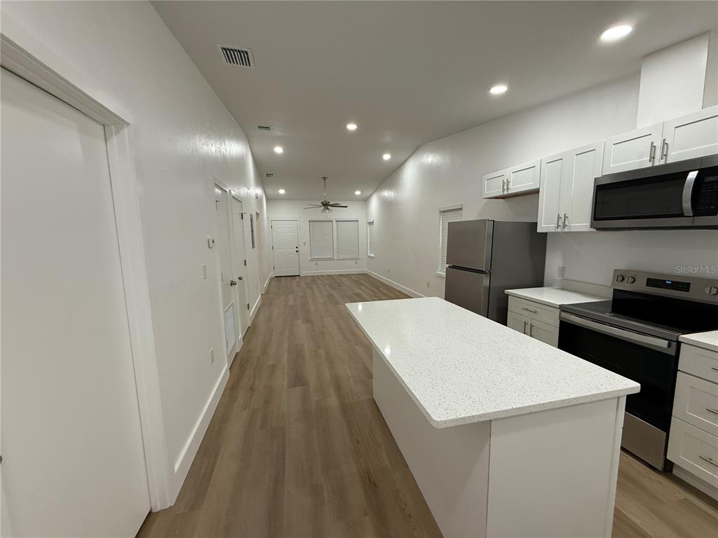 A kitchen with a white island, stainless steel appliances, and wood-look flooring — 7020 SW 45TH AVENUE, GAINESVILLE, FL
