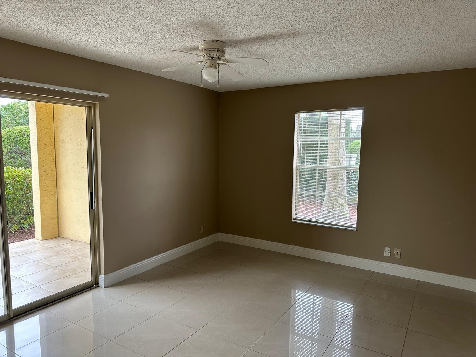 An empty room with beige walls, tile flooring, a ceiling fan, and a sliding glass door — 6283 La Costa Drive # D, Boca Raton FL 33433, BOCA RATON, FL