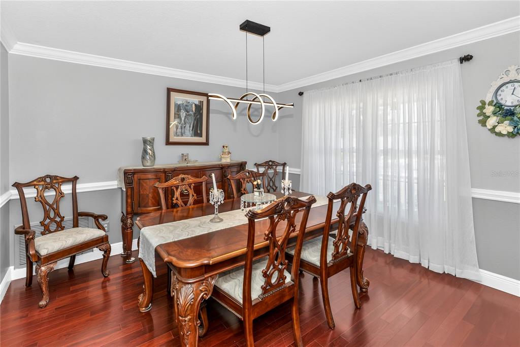 A formal dining room features a wooden table, ornate chairs, a sideboard, and a modern chandelier — 2031 TOURNAMENT DRIVE, APOPKA, FL