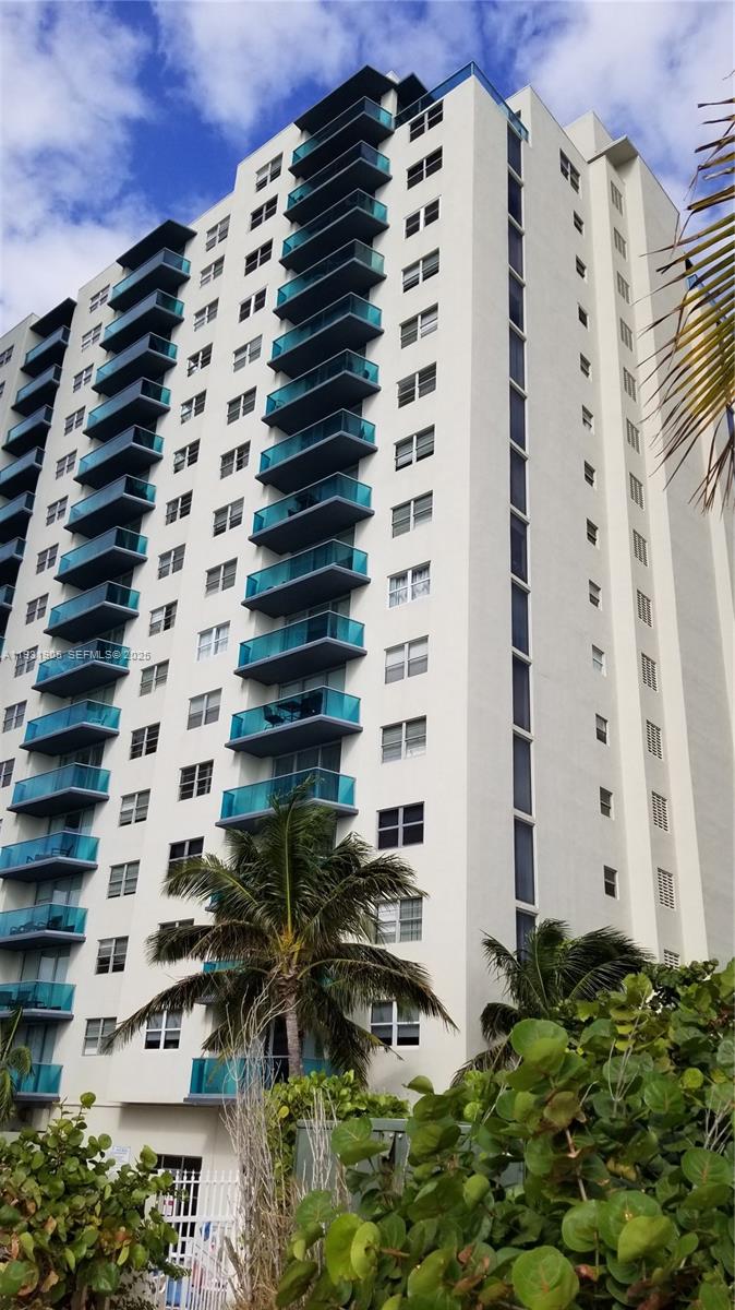 A tall, white residential high-rise building features stacked balconies with blue glass railings — 4001 S Ocean Dr # 4J, Hollywood FL 33019, HOLLYWOOD, FL