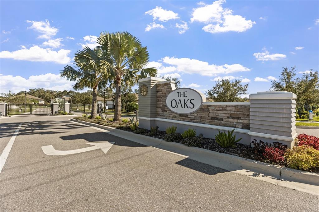 A stone and siding entrance monument for a community named The Oaks — 6248 BRADFORD WOODS DR, ZEPHYRHILLS, FL