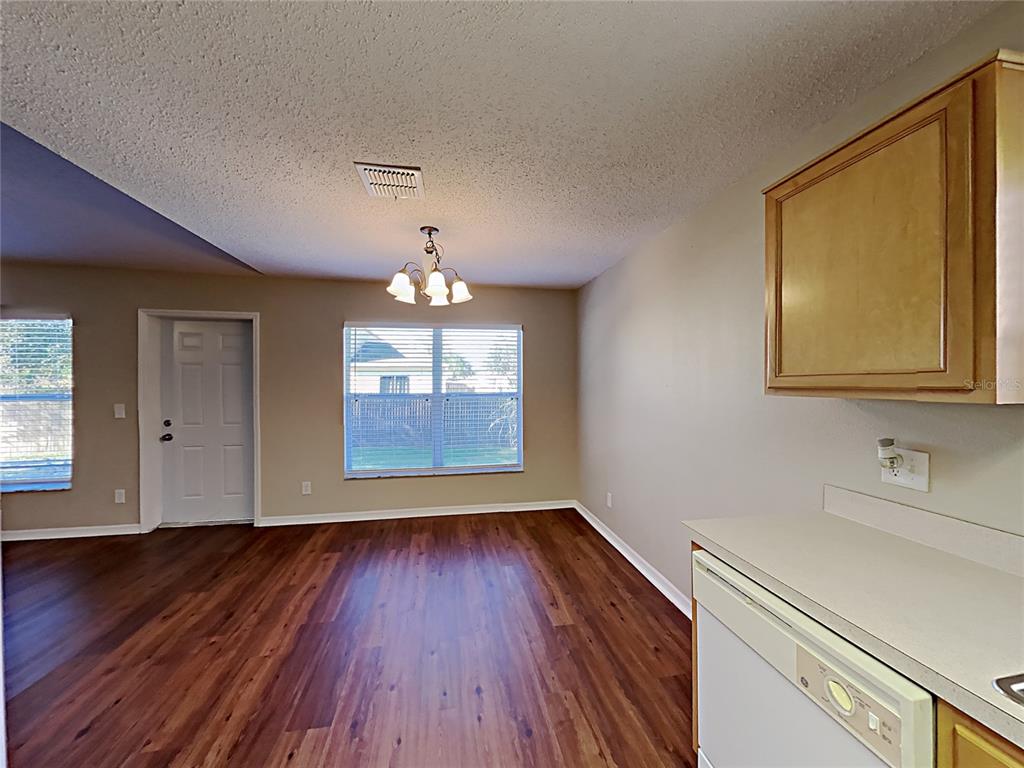 A dining area with wood-look flooring, a chandelier, and an adjacent kitchen counter — 1745 PILCHARD DRIVE, POINCIANA, FL