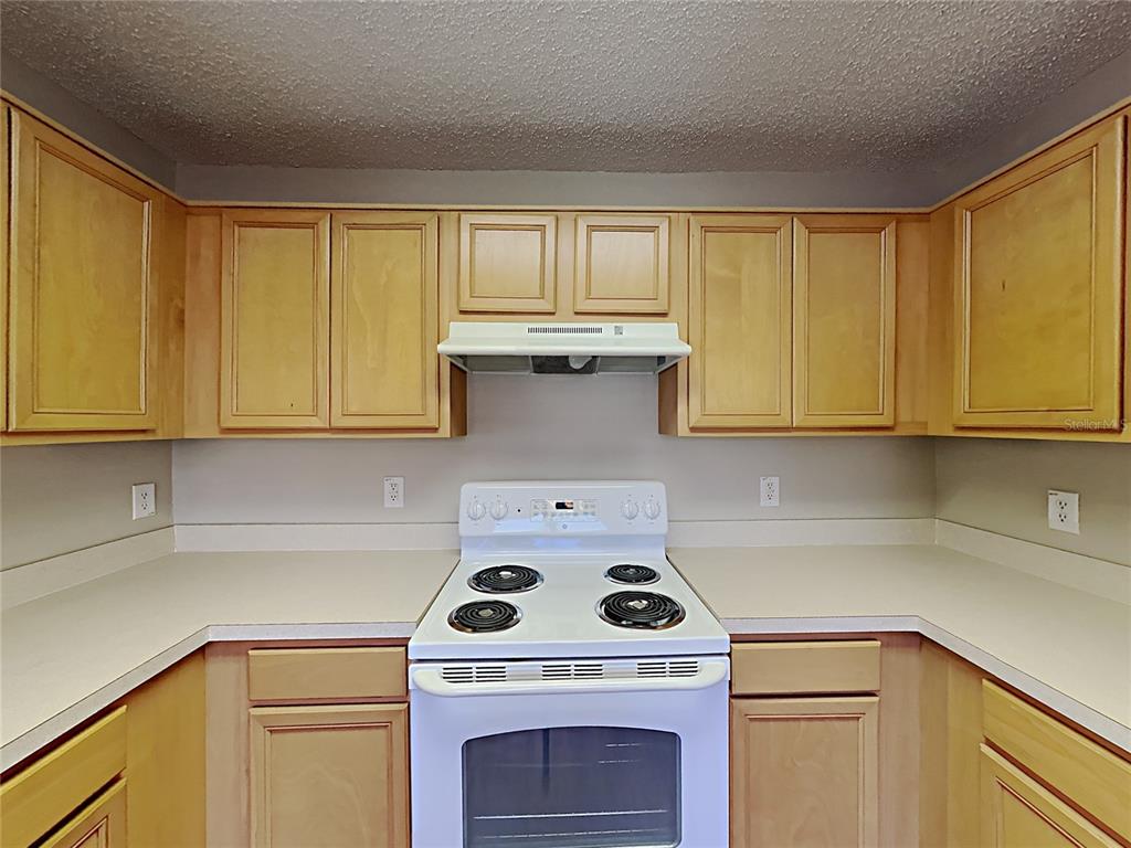 A kitchen features light wood cabinets, white appliances, and a white countertop — 1745 PILCHARD DRIVE, POINCIANA, FL