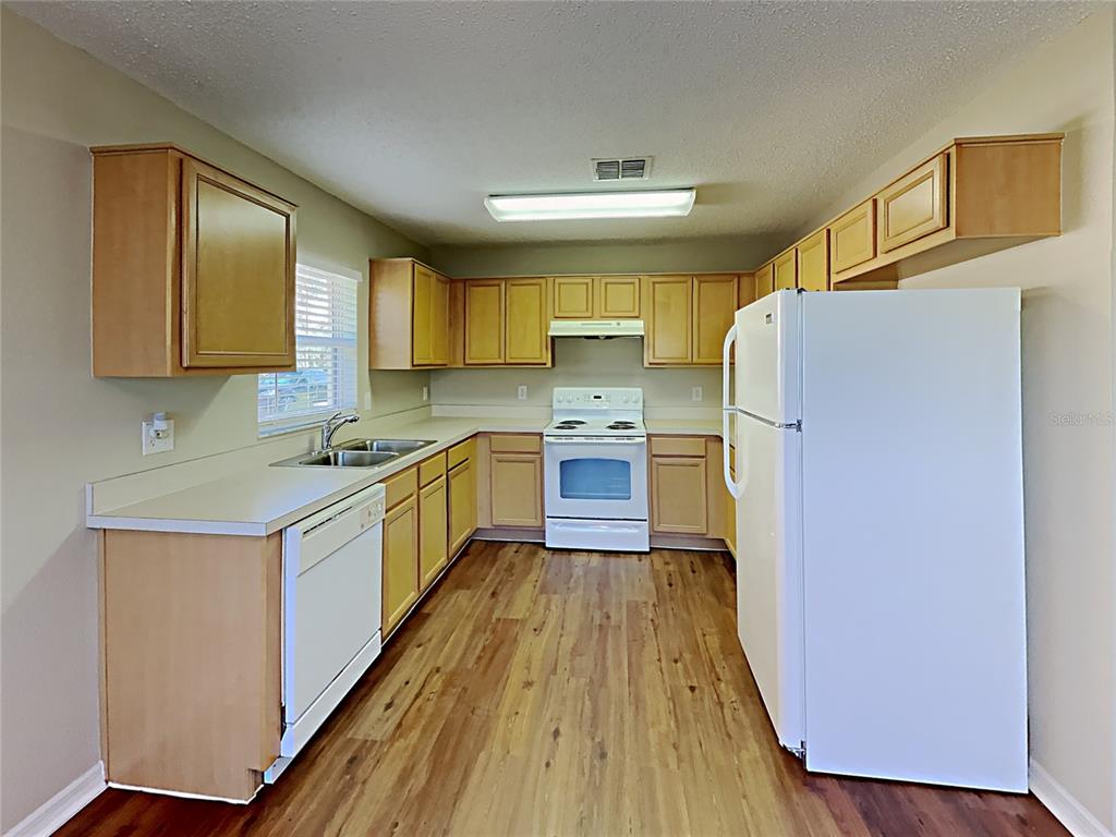 A kitchen with light wood cabinets, white appliances, and wood-look flooring — 1745 PILCHARD DRIVE, POINCIANA, FL