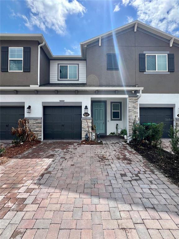 A two-story townhouse with a paved driveway, a single-car garage, and a teal front door — 5222 TYSON RANCH BOULEVARD, ORLANDO, FL