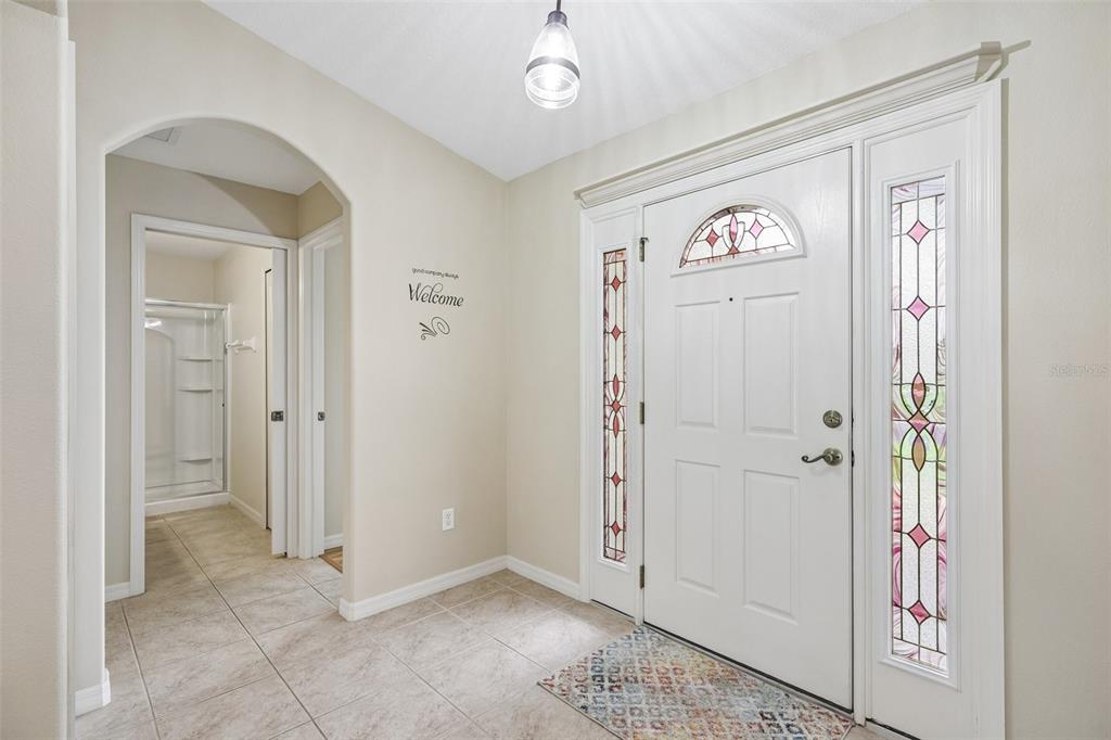 An entryway features tile flooring, a white front door with stained glass, and an arched opening — 1056 SW 159TH STREET, OCALA, FL