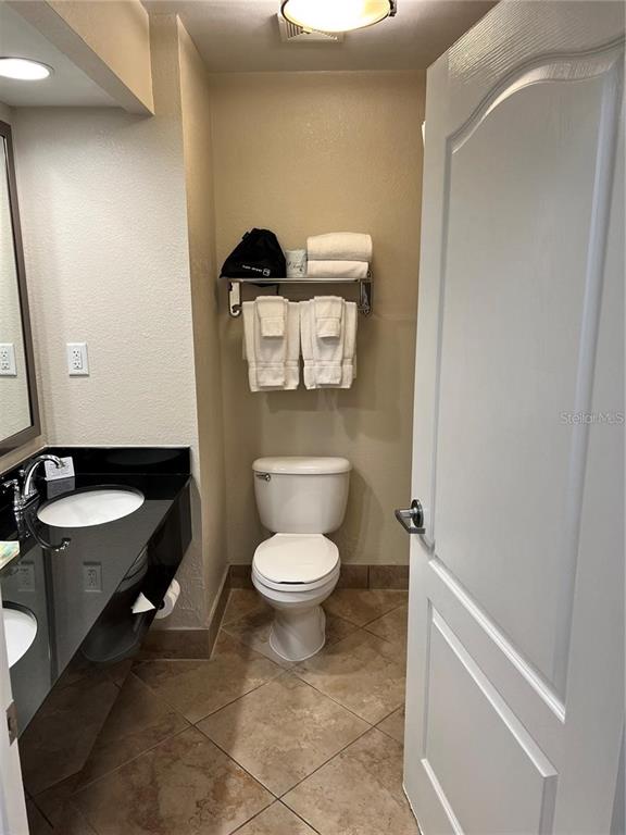 A bathroom features a black vanity countertop, a white toilet, and a towel rack — 3000 MAINGATE LANE UNIT 228, KISSIMMEE, FL