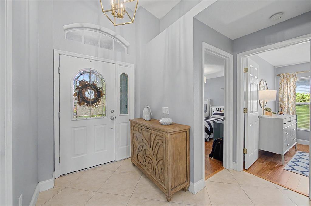 An entryway features a white front door, a wooden console table, and light-colored tile flooring — 5418 TWIN CREEKS DRIVE, VALRICO, FL