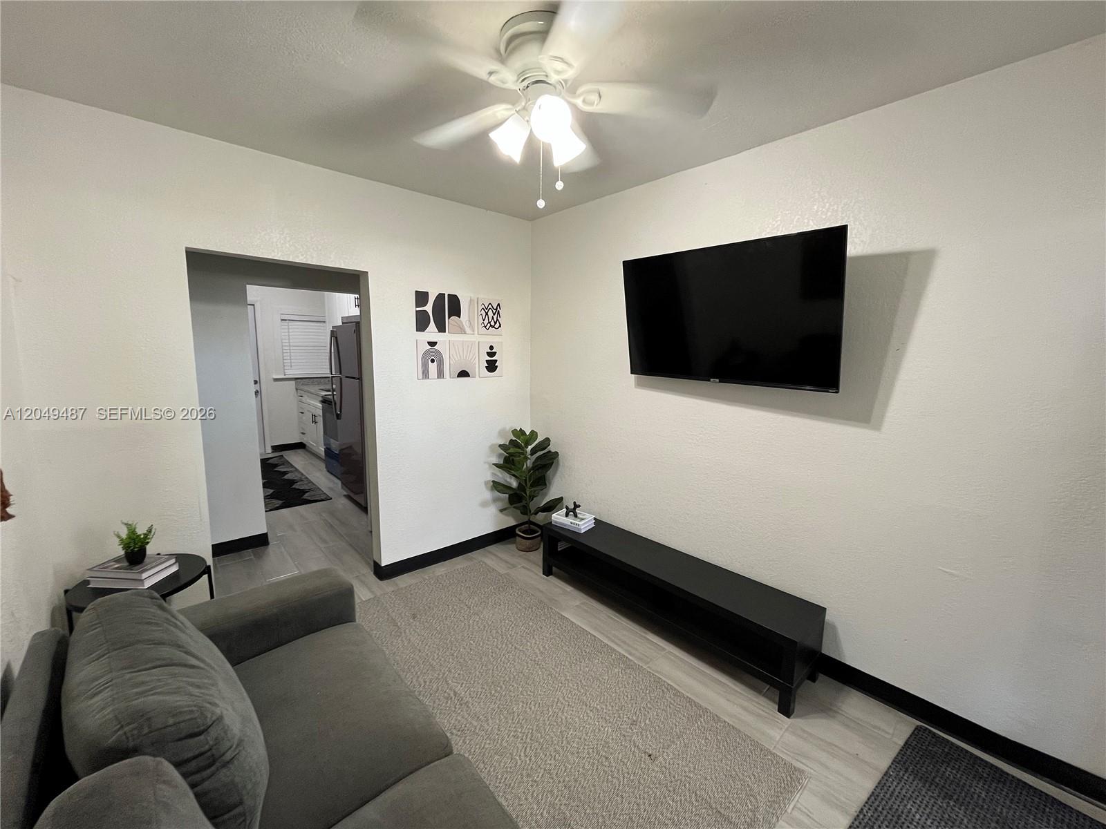 A living room features a wall-mounted television, a black media console, and a gray sofa — 140 NW 13th St, Miami FL 33136, MIAMI, FL