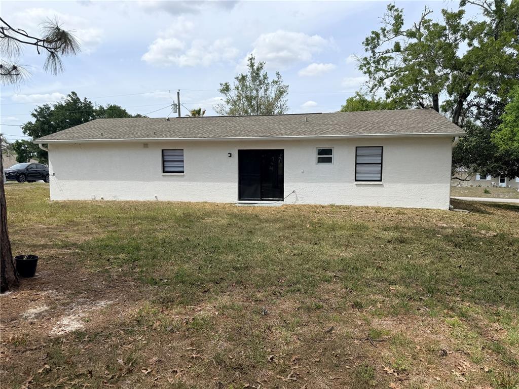 The rear exterior of a single-story house features a sliding glass door and three windows — 13186 THRUSH STREET, SPRING HILL, FL