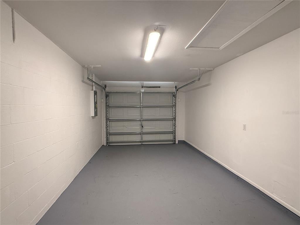 An empty garage with white block walls, a gray painted floor, and a sectional door — 13186 THRUSH STREET, SPRING HILL, FL