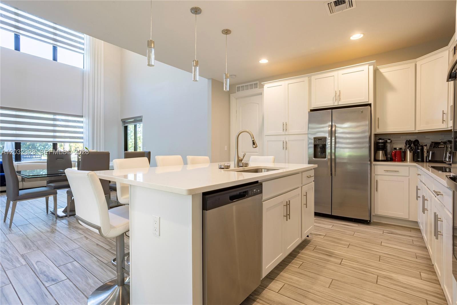 A modern kitchen features white cabinets, stainless steel appliances, and a central island with seating — 10069 Brickhill Dr # 10069, Boca Raton FL 33428, BOCA RATON, FL