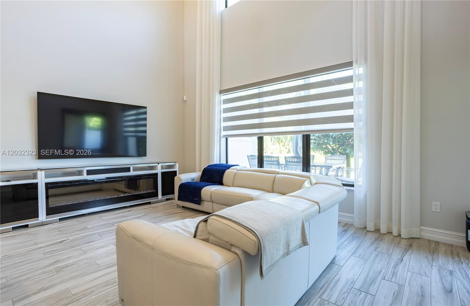 A living room features a white sectional sofa, a wall-mounted television, and a fireplace console — 10069 Brickhill Dr # 10069, Boca Raton FL 33428, BOCA RATON, FL