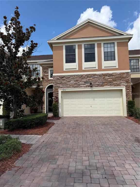 A two-story house features a stone facade, a two-car garage, and a paved driveway — 1413 PORTOFINO MEADOWS BOULEVARD, ORLANDO, FL