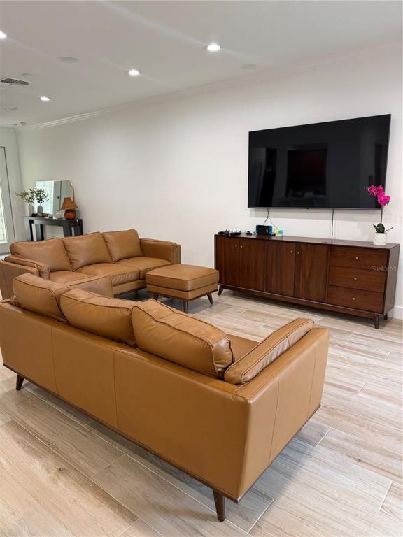 A living room features tan leather sofas, a wooden media console, and light-colored tile flooring — 1413 PORTOFINO MEADOWS BOULEVARD, ORLANDO, FL