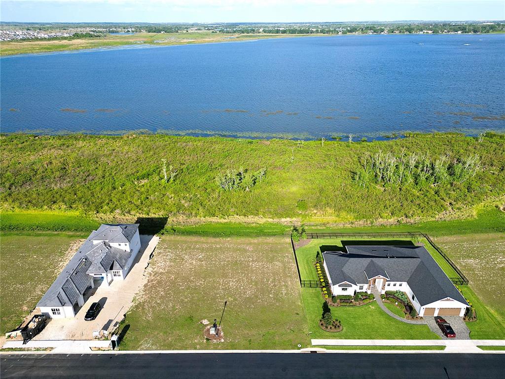 An aerial view shows two houses separated by a vacant lot facing a large lake — 328 CALADIUM AVENUE, LAKE ALFRED, FL