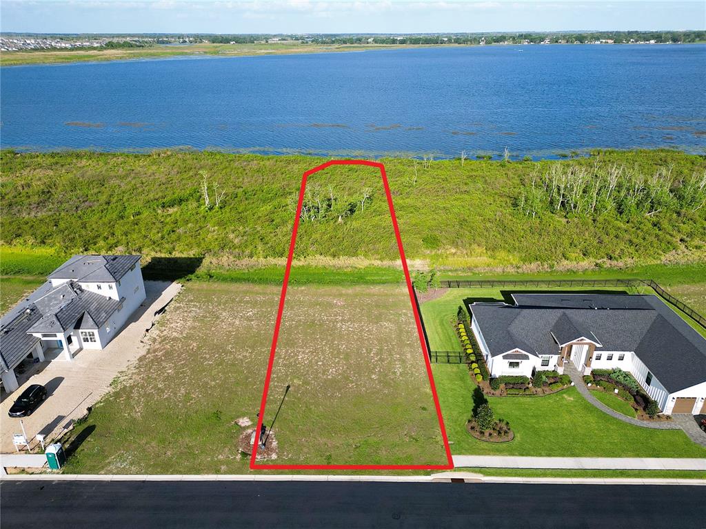 An aerial view shows a vacant residential lot outlined in red bordering a large lake — 328 CALADIUM AVENUE, LAKE ALFRED, FL