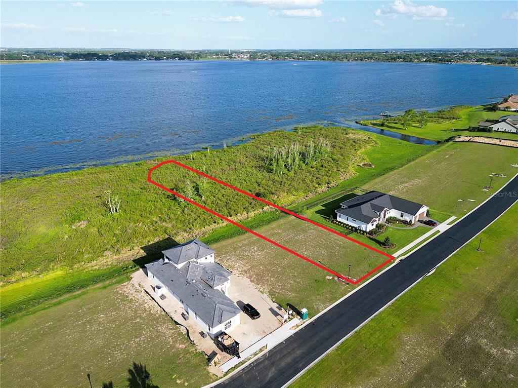 An aerial view shows a vacant rectangular lot situated between two houses near a lake — 328 CALADIUM AVENUE, LAKE ALFRED, FL
