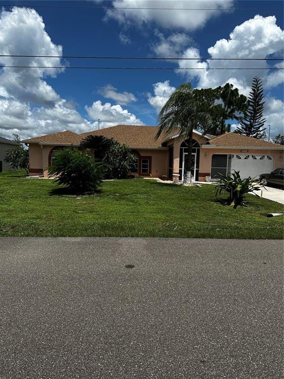 A single-story peach-colored house with a brown shingled roof and a front-facing garage — 23174 RANGER AVENUE, PORT CHARLOTTE, FL