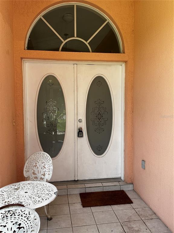 A white double front door with oval glass inserts sits under an arched transom window — 23174 RANGER AVENUE, PORT CHARLOTTE, FL