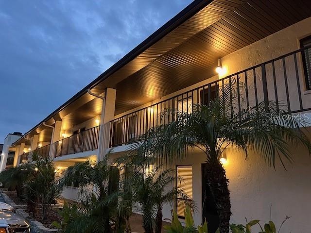 An exterior view of a two-story apartment building with balconies and palm trees at dusk — 7205 CURTISS AVENUE UNIT 2F, SARASOTA, FL
