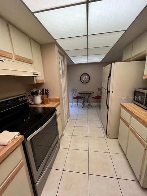 A kitchen features light-colored cabinets, stainless steel appliances, and a small dining area at the end — 7205 CURTISS AVENUE UNIT 2F, SARASOTA, FL