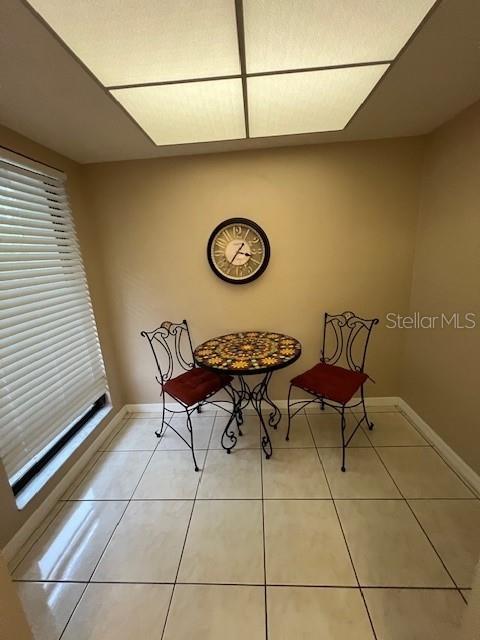 A small dining nook features a round mosaic table, two metal chairs, and a wall clock — 7205 CURTISS AVENUE UNIT 2F, SARASOTA, FL