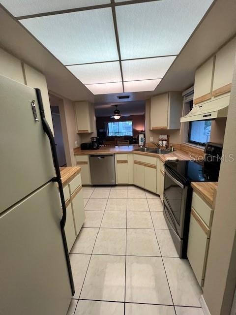 A kitchen features light-colored cabinets, tile flooring, stainless steel appliances, and a drop ceiling — 7205 CURTISS AVENUE UNIT 2F, SARASOTA, FL
