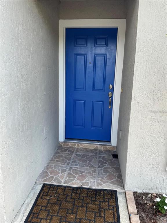 A bright blue front door is set within a recessed entryway with tiled flooring — 2194 CYPRESS BAY BOULEVARD, KISSIMMEE, FL