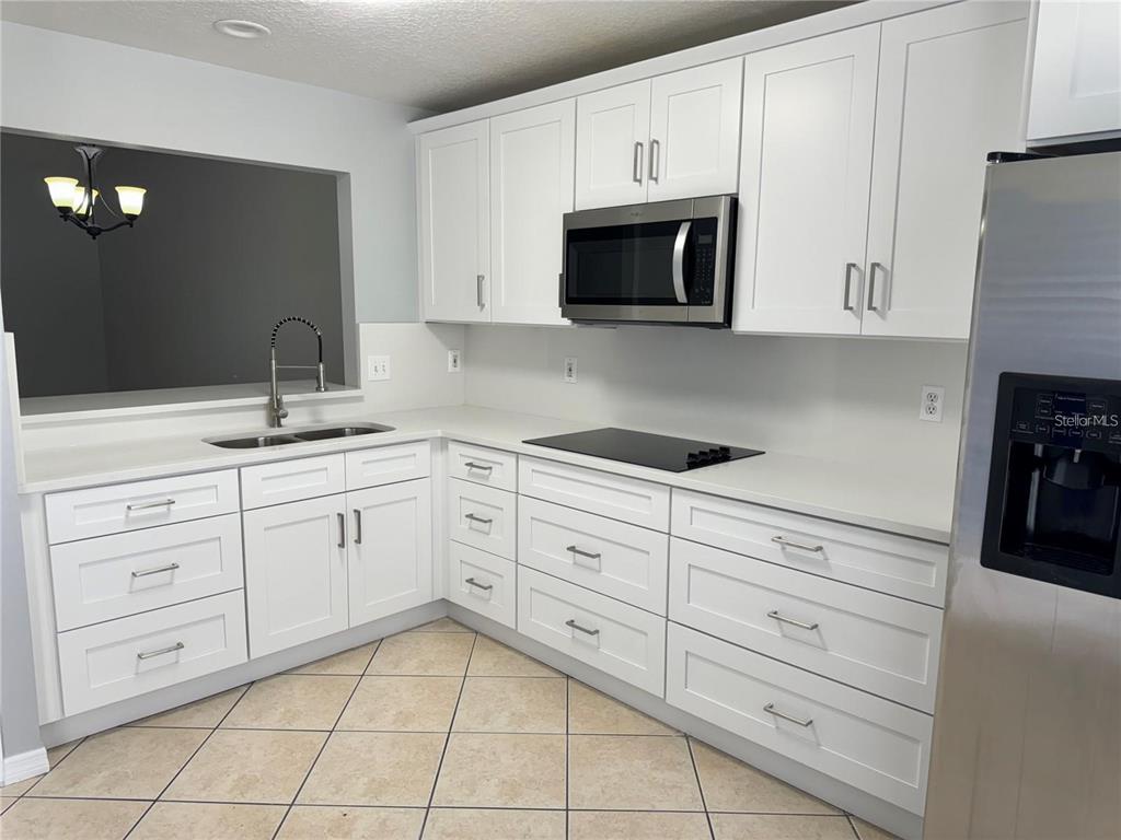 A kitchen features white shaker cabinets, stainless steel appliances, and light-colored countertops — 2194 CYPRESS BAY BOULEVARD, KISSIMMEE, FL