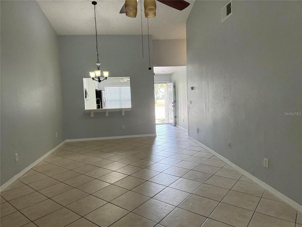 A living area with light gray walls, tile flooring, a ceiling fan, and a pass-through window — 2194 CYPRESS BAY BOULEVARD, KISSIMMEE, FL