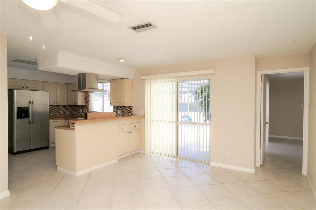 A kitchen with light cabinets and a stainless steel refrigerator opens to a dining area — 1306 GOLFVIEW DRIVE, DAYTONA BEACH, FL