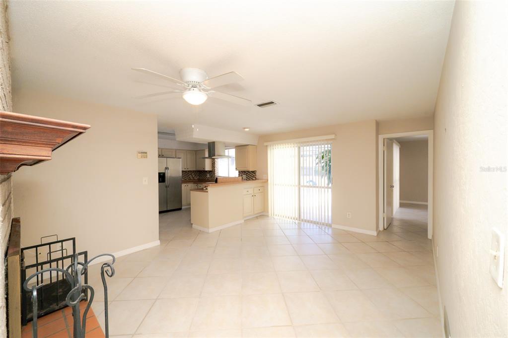 An open-concept living area features tile flooring, a ceiling fan, and an adjacent kitchen — 1306 GOLFVIEW DRIVE, DAYTONA BEACH, FL