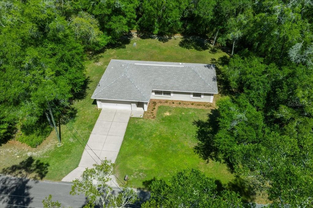 An aerial view shows a single-story house with a gray roof and concrete driveway — 3597 E JONAH PLACE, INVERNESS, FL