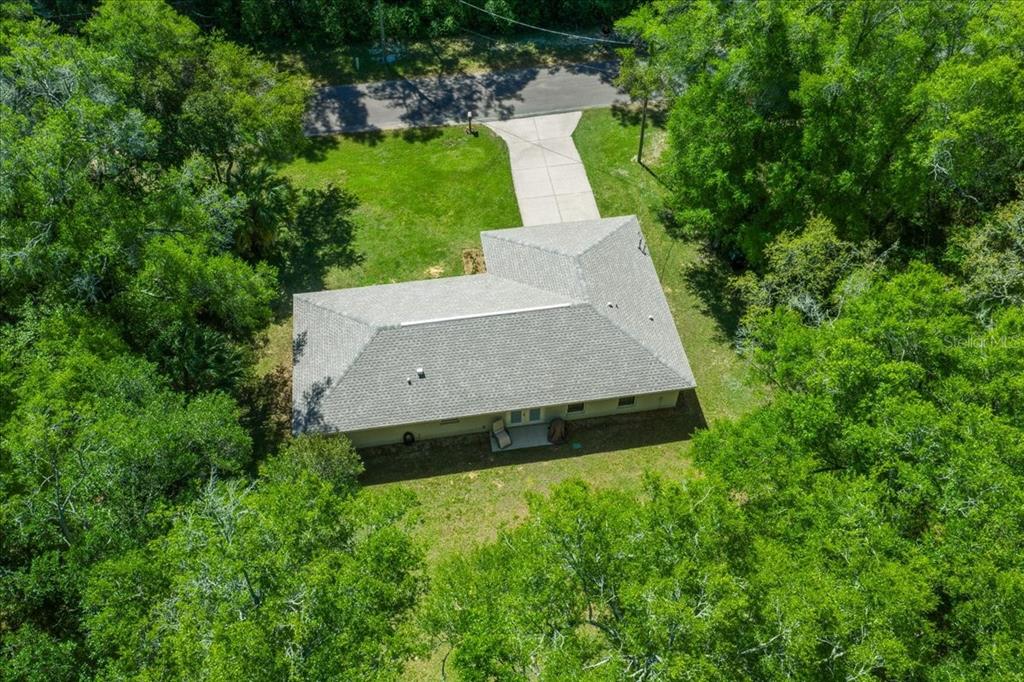 An aerial view shows a single-story house with a gray roof surrounded by dense trees — 3597 E JONAH PLACE, INVERNESS, FL