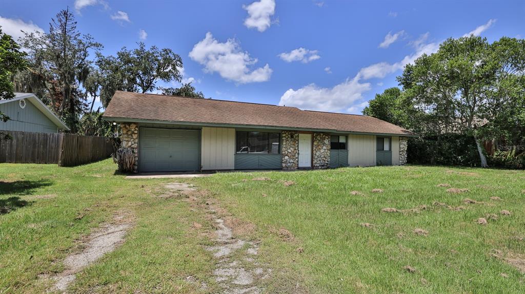 A single-story house with a stone facade, attached garage, and a large grassy front yard — 2508 PINE TREE DRIVE, EDGEWATER, FL