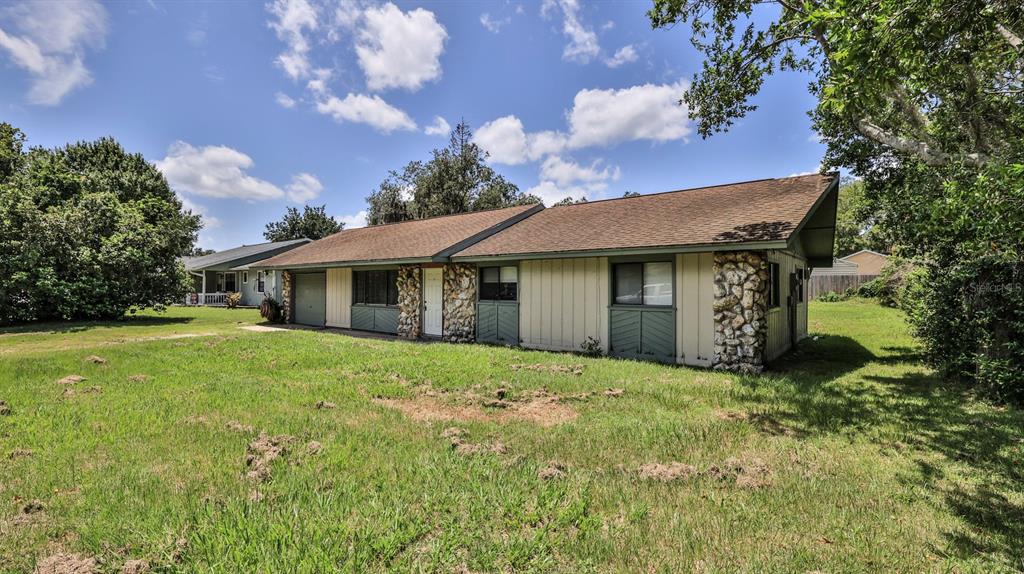 A single-story house with light-colored siding, stone accents, and a brown shingled roof — 2508 PINE TREE DRIVE, EDGEWATER, FL