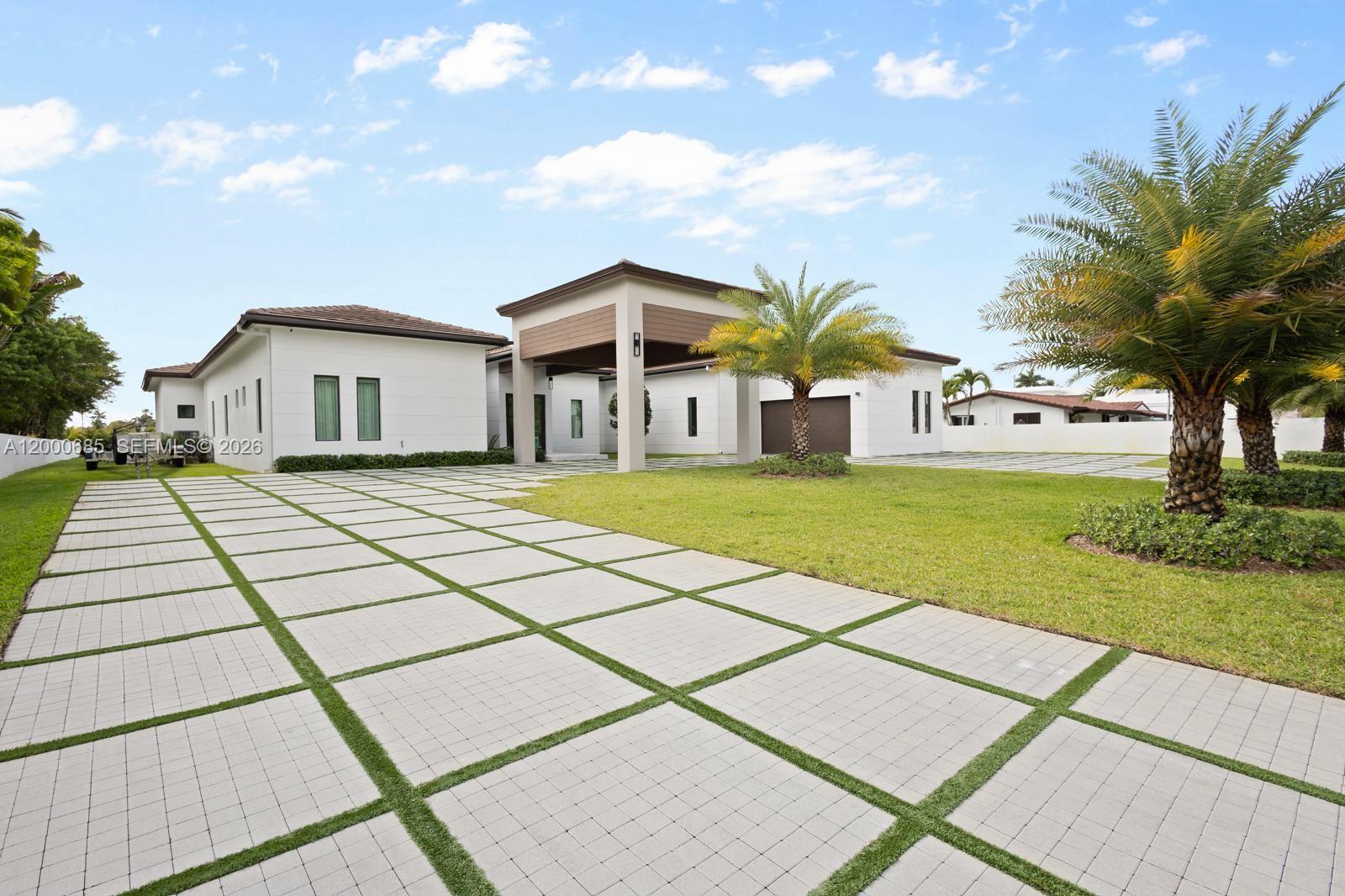 A modern white house features a large paver driveway with grass strips and palm trees — 80 NW 129th Ave, Miami FL 33182, MIAMI, FL
