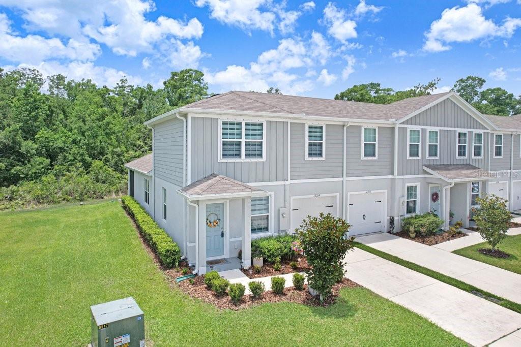 An exterior view of a two-story gray townhouse with a light blue front door — 12214 GRIZZLY LANE, NEW PORT RICHEY, FL